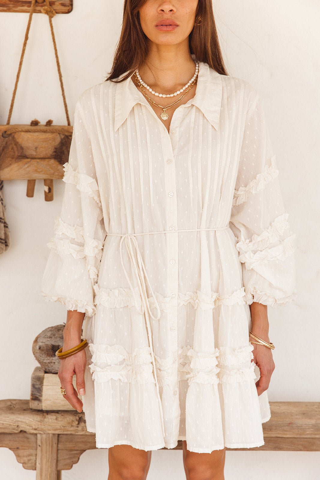 Woman wearing a white dress with ruffled details in a rustic setting
