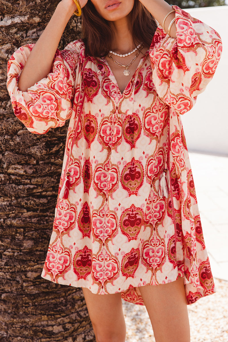 Woman wearing a red and white patterned dress against a natural background