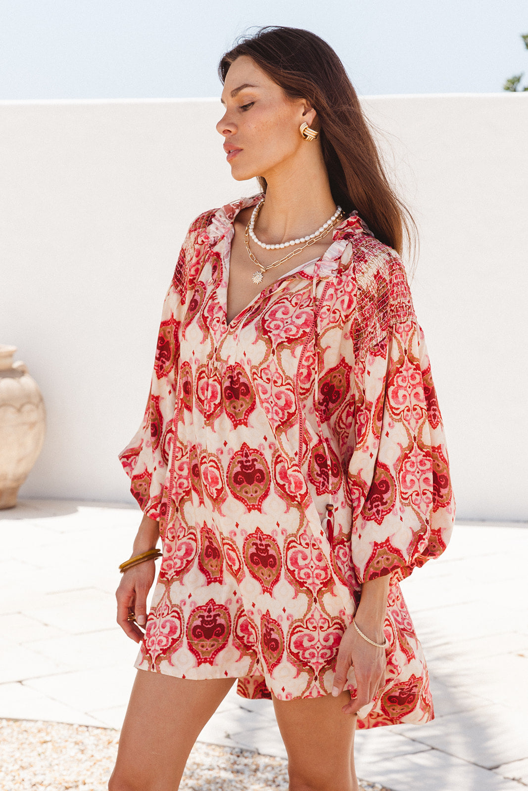Woman wearing a red and white patterned dress standing outdoors.