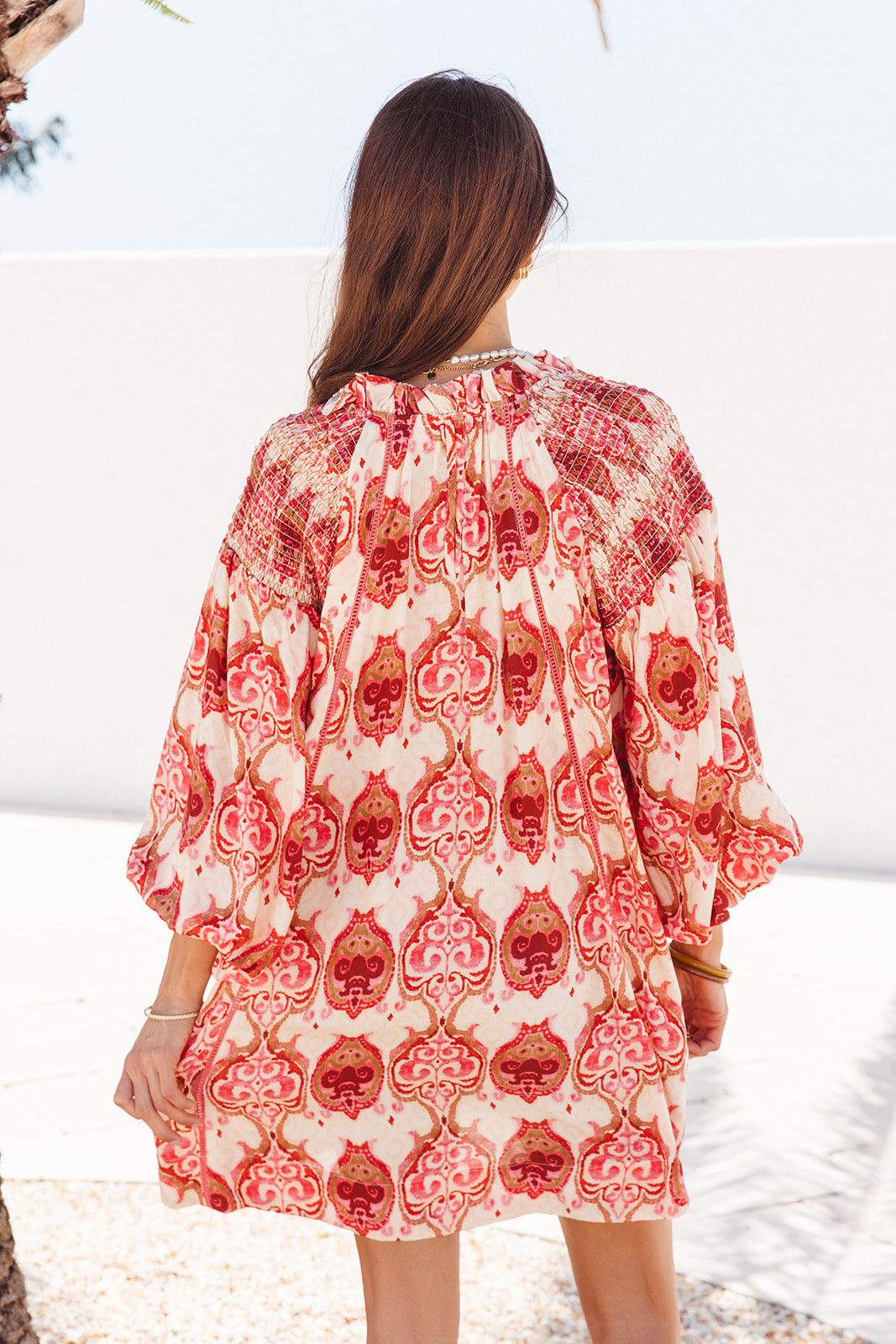 Woman wearing a red and white patterned dress on a beach.