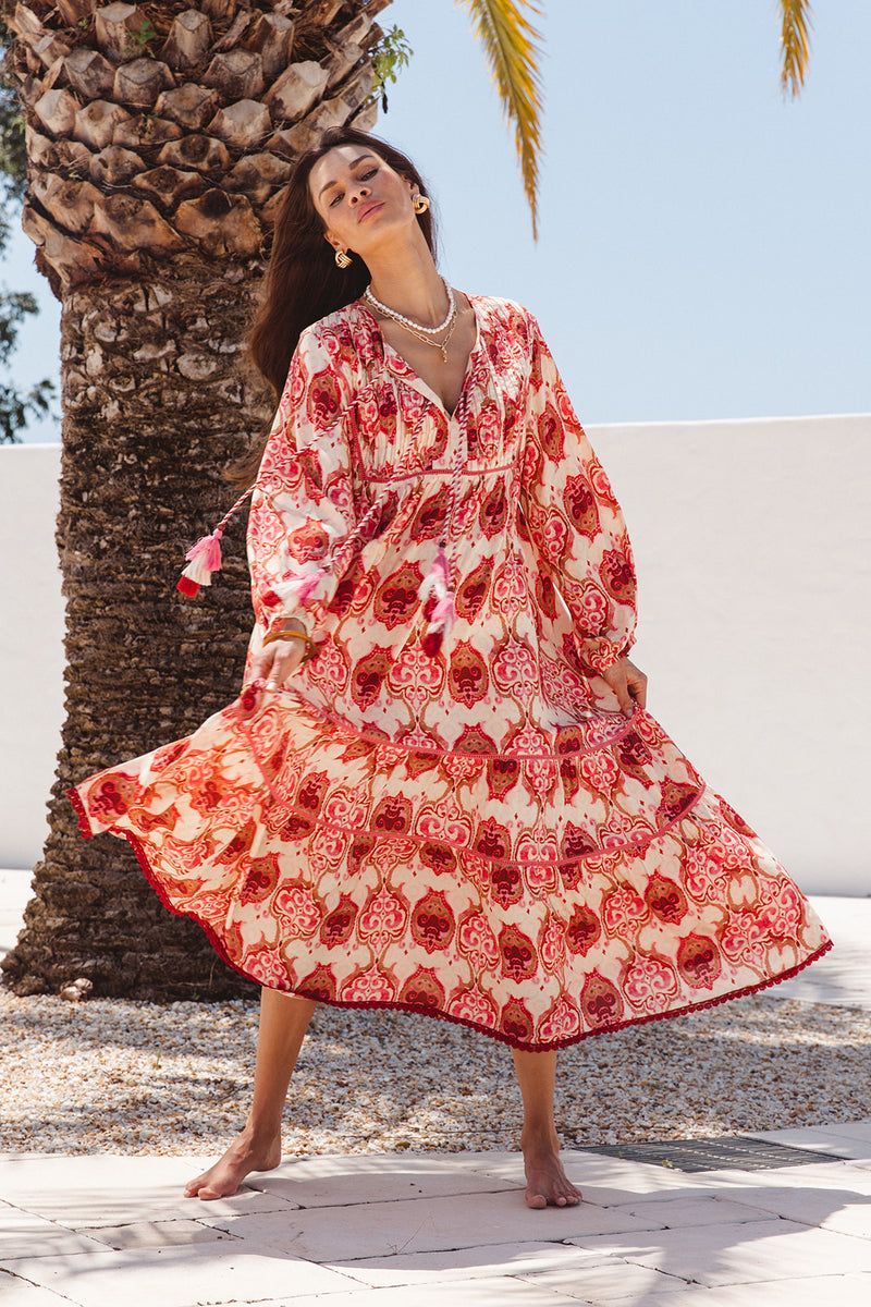 Woman in a red and white patterned dress standing next to a palm tree
