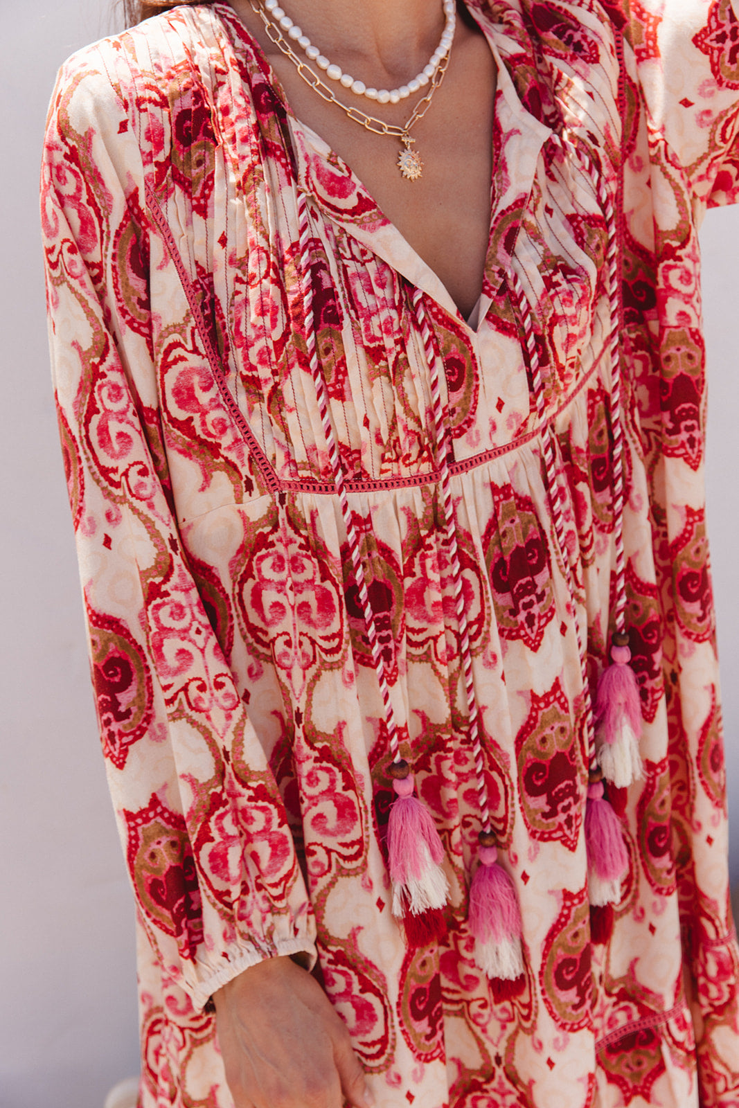 Red and white patterned dress with tassels on a plain background
