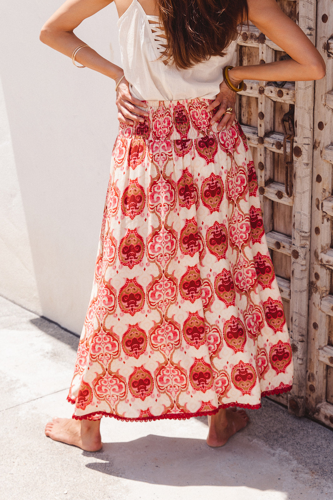 Person wearing a red and white patterned wide pants standing against a textured wall.