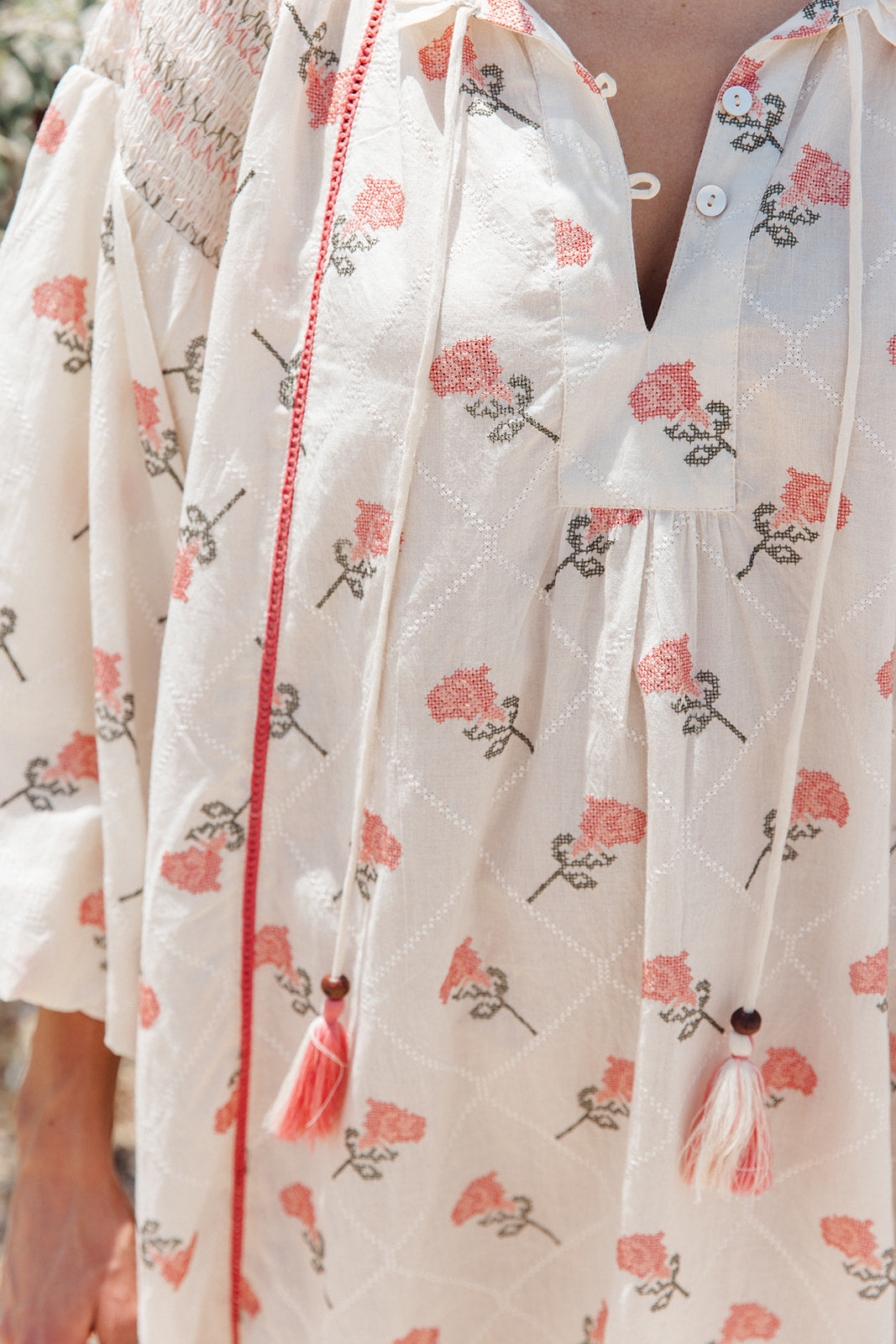 Close-up of a floral-patterned garment with tassels on a blurred background