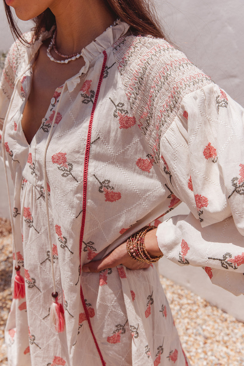 Woman wearing a white floral dress with a neutral background