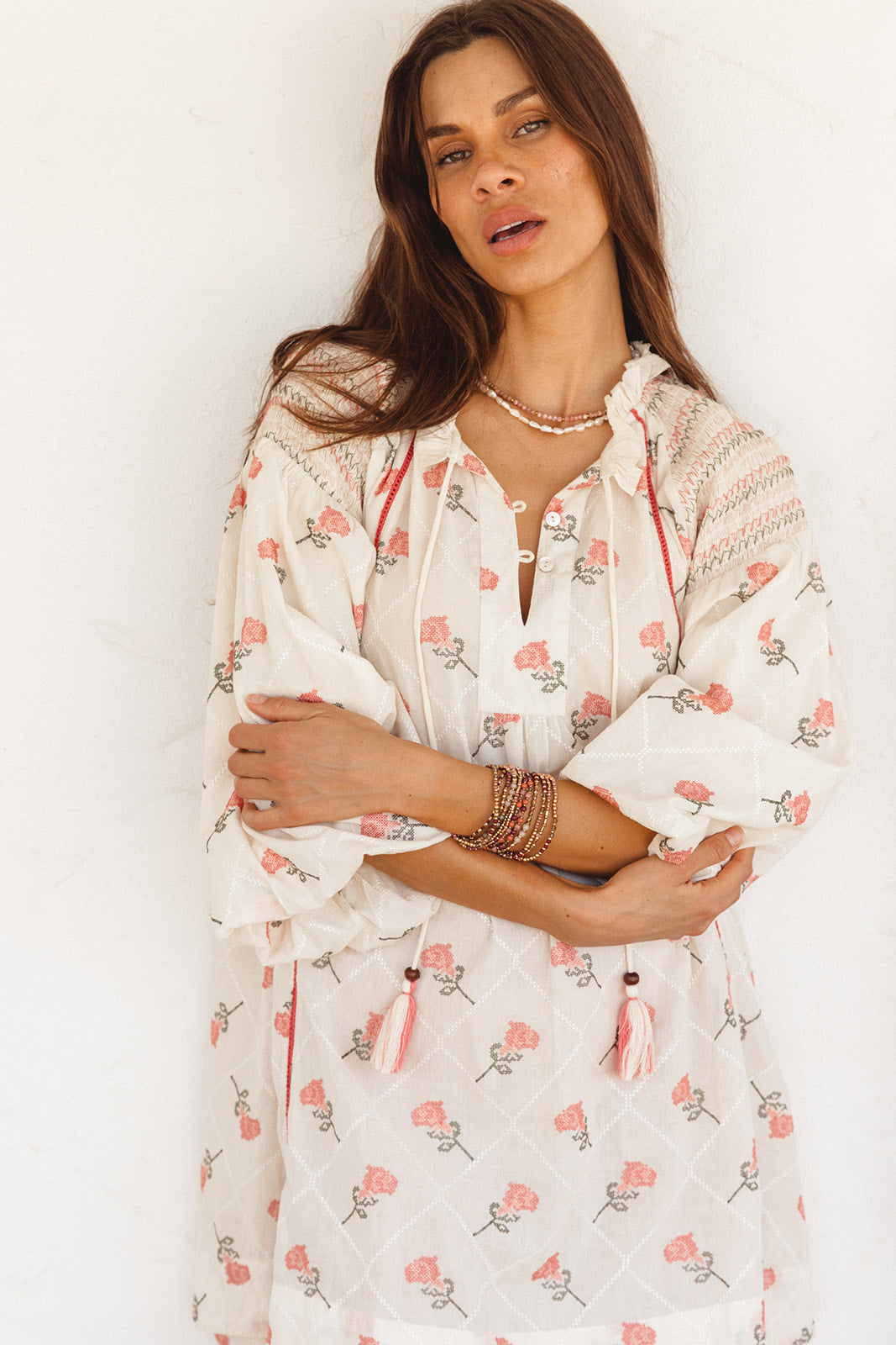 Woman wearing a white floral dress with a plain background