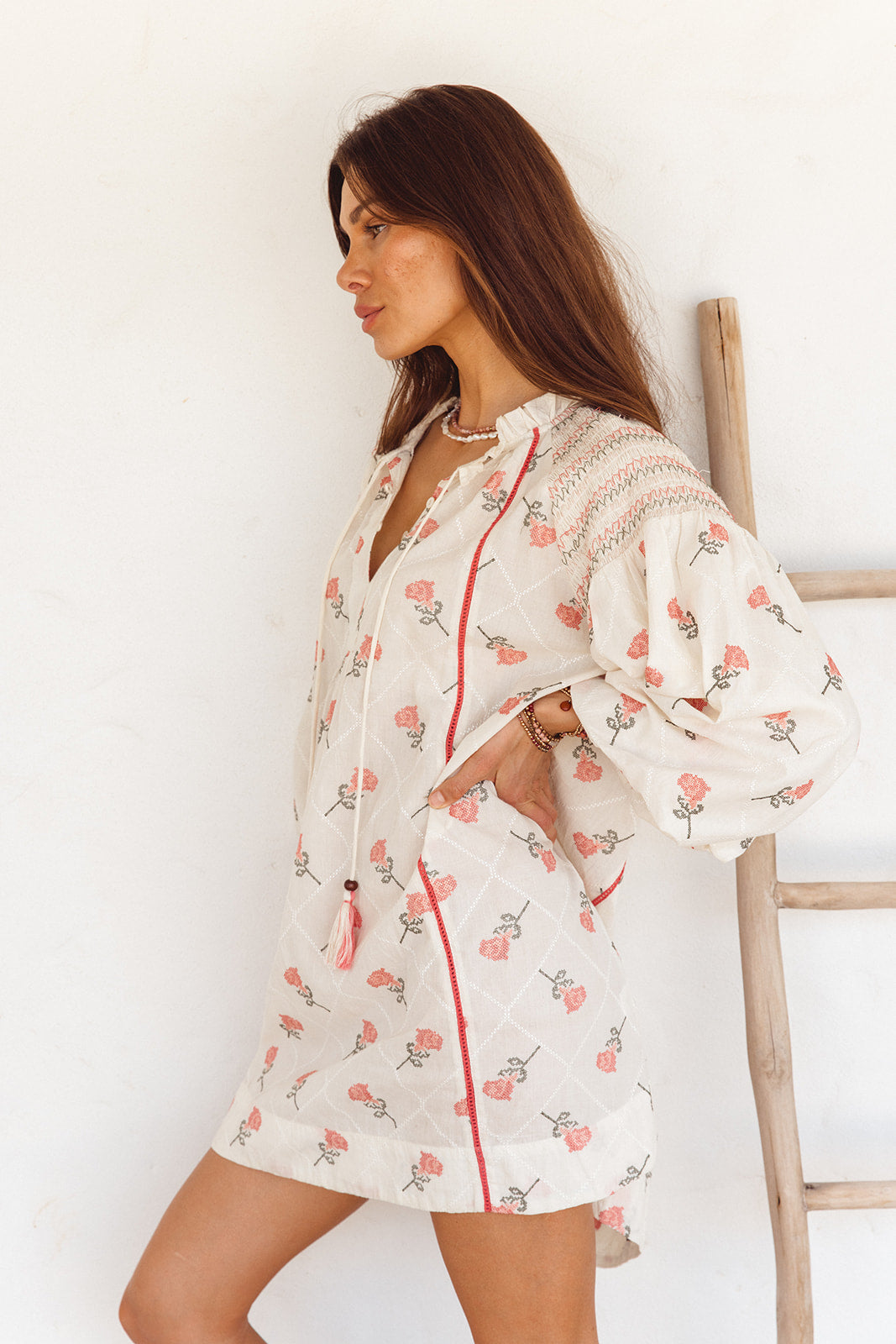 Woman wearing a floral dress with red accents against a white background