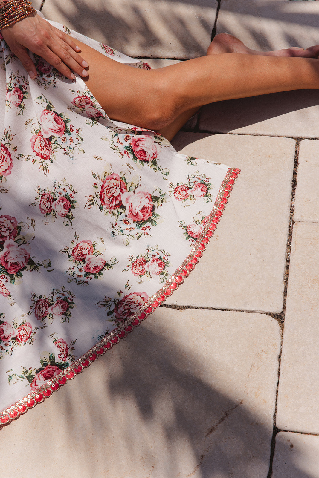 Person wearing a floral dress with pink roses on a stone pavement