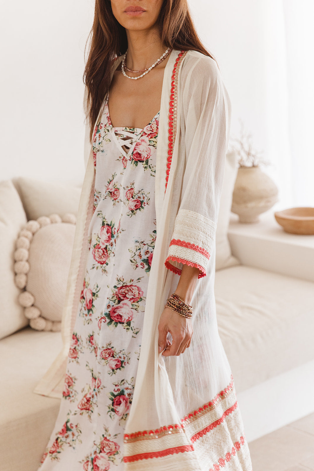 Woman wearing a floral dress with a matching cover up in a bright room.