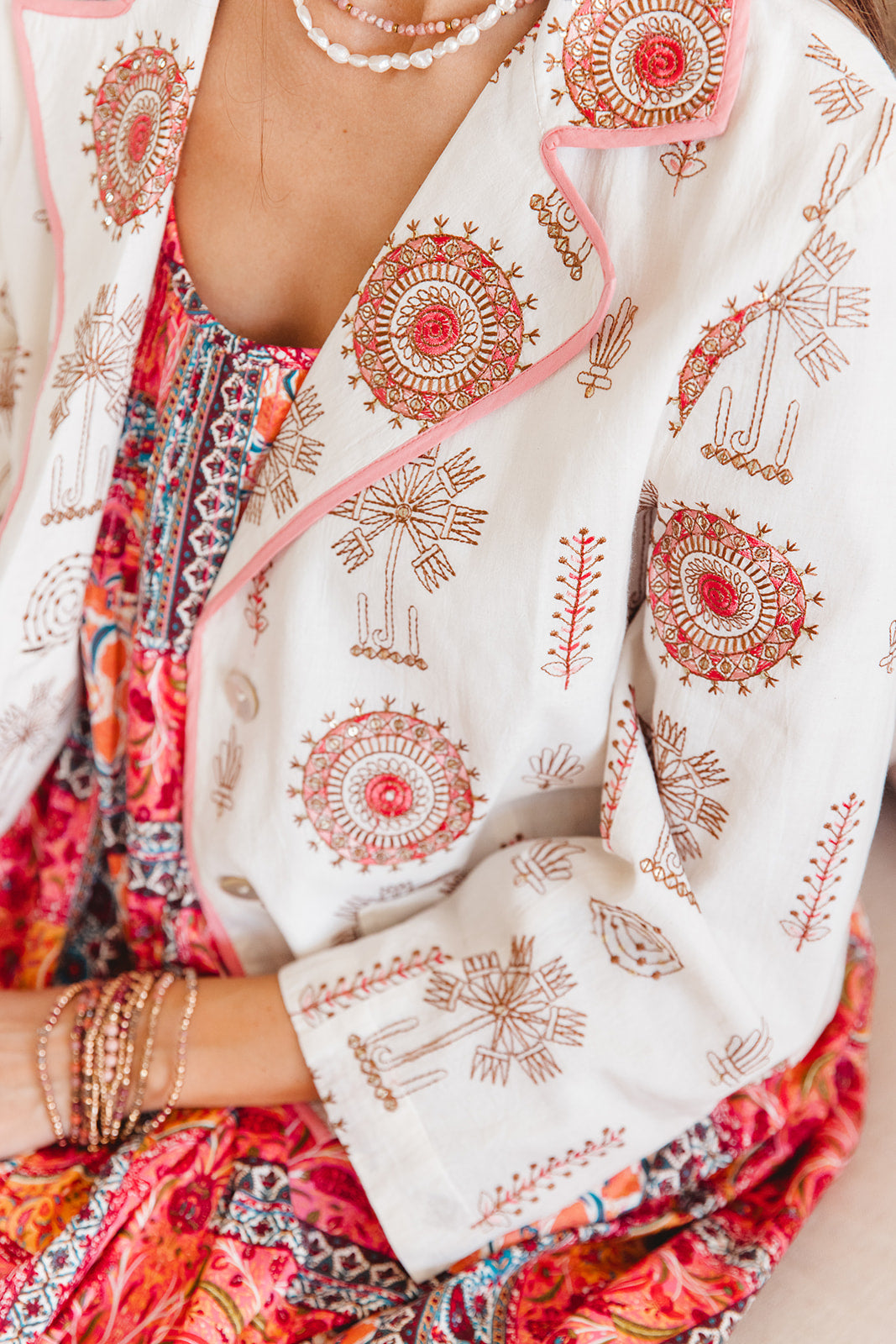 Close-up of a person wearing a colorful outfit with a white jacket featuring red and gold patterns.