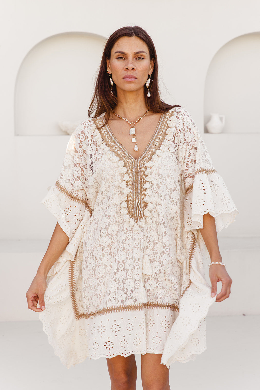 Woman wearing a white lace dress with a plain background