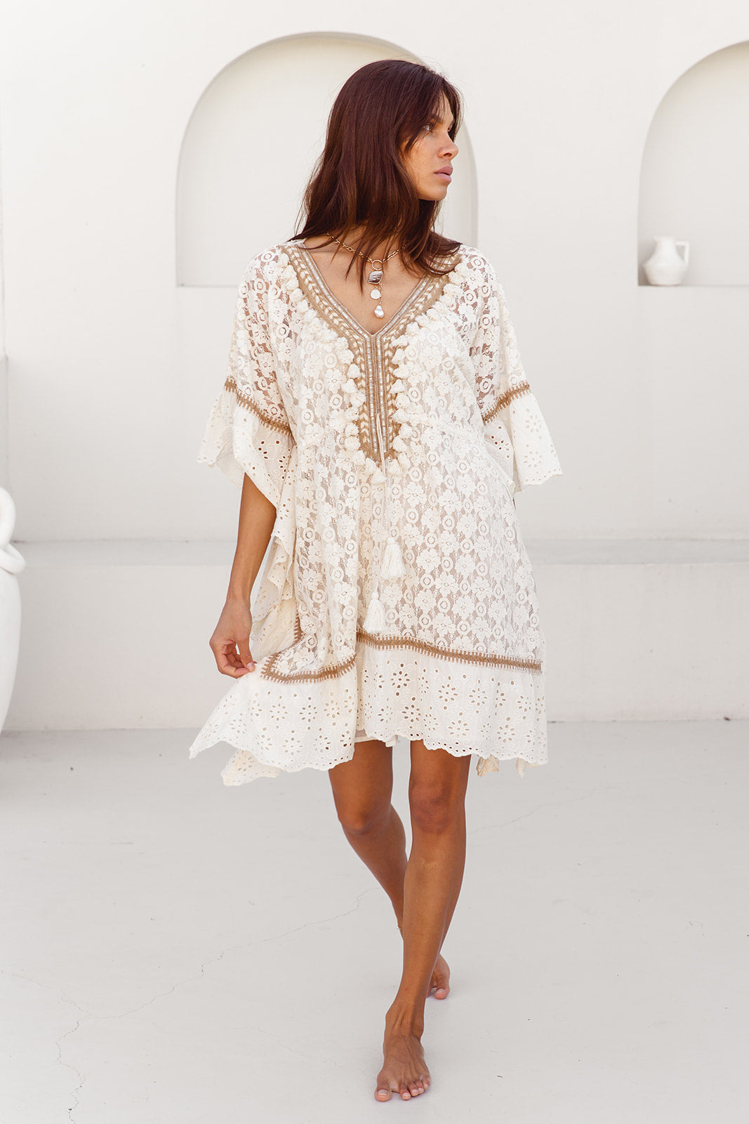 Woman wearing a white lace dress with a plain white background