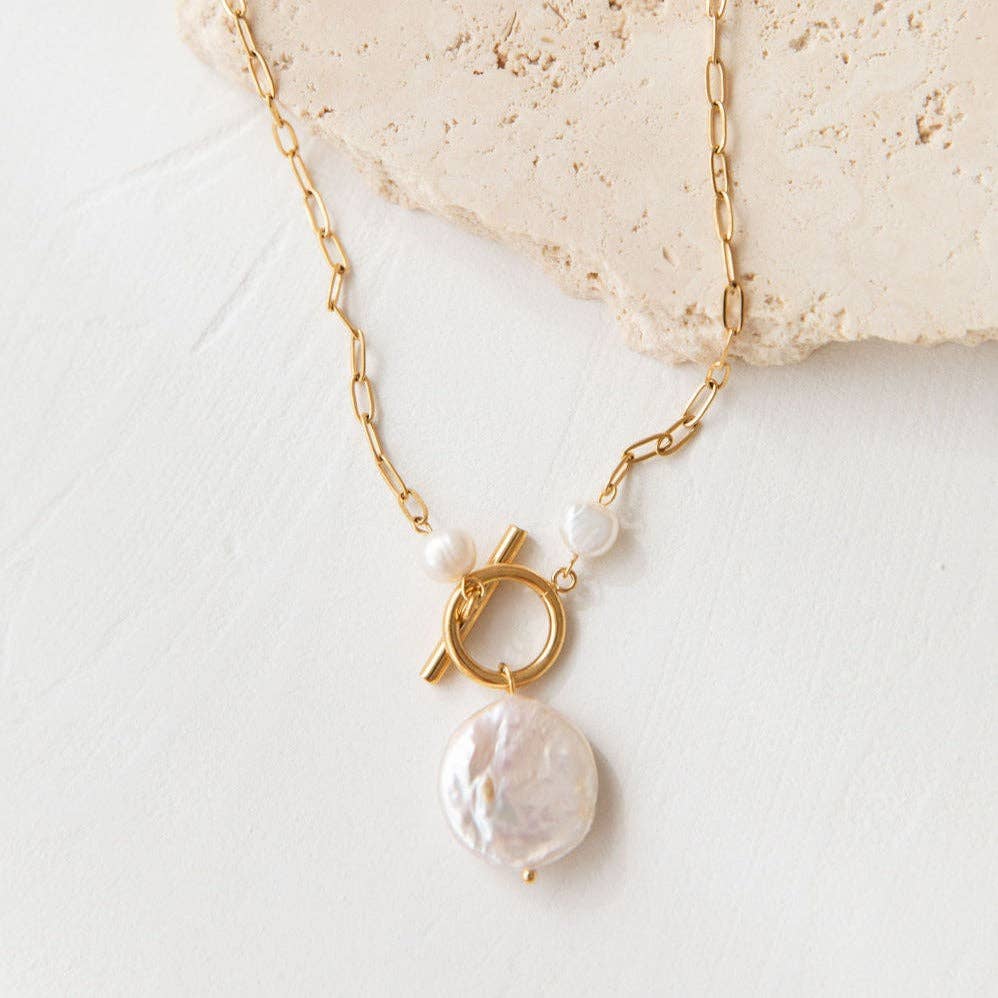Gold necklace with pearl pendants on a light background