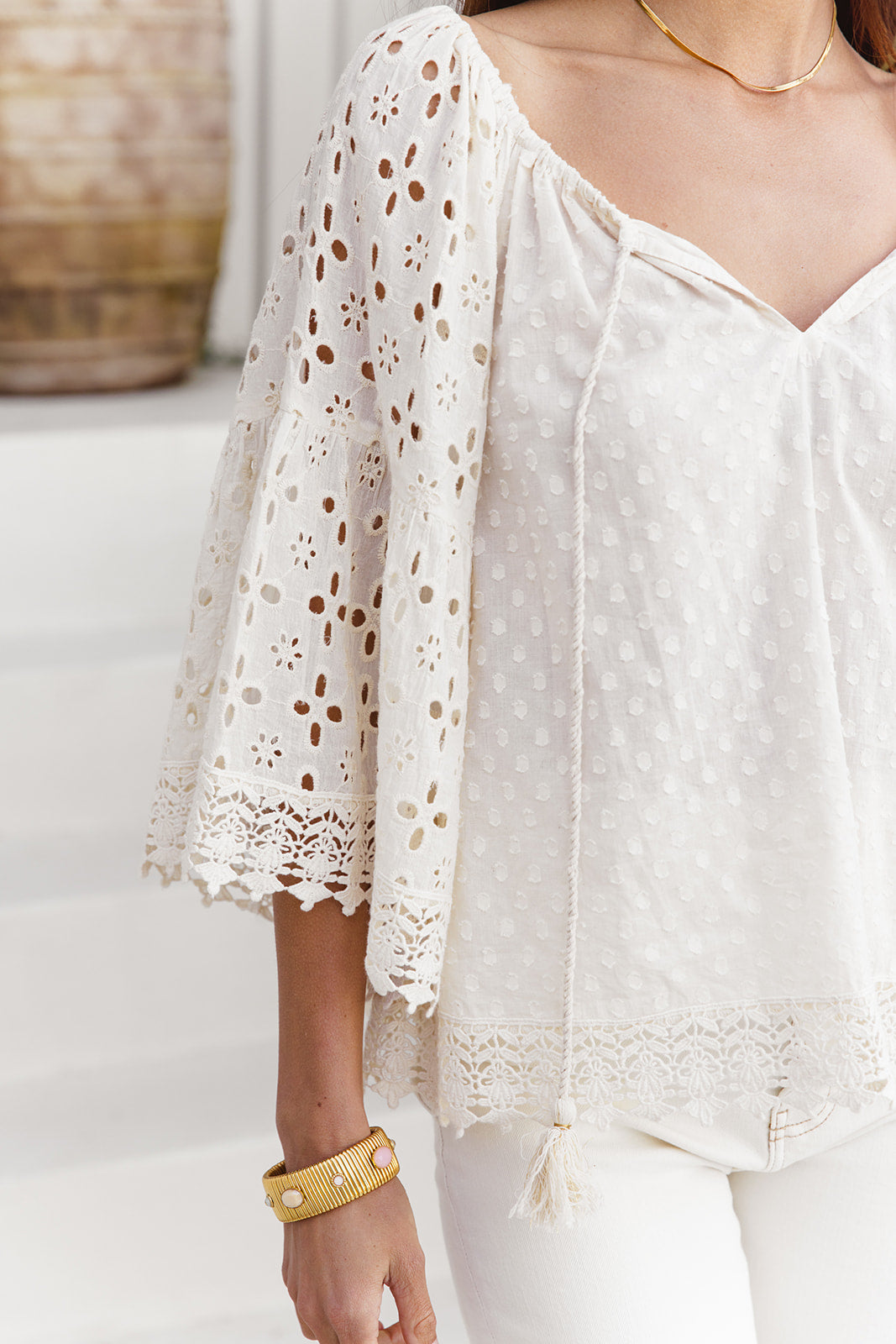 White lace top worn by a person with a blurred background